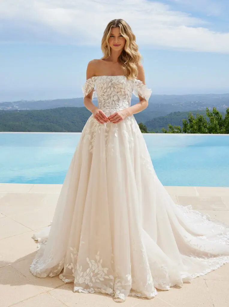 Romantische Braut in einem schulterfreien A-Linien-Brautkleid mit zarter Spitze. Eine perfekte Kombination aus Eleganz und Leichtigkeit für eine unvergessliche Hochzeit – exklusive Brautmode in Essen, Düsseldorf und Wuppertal.