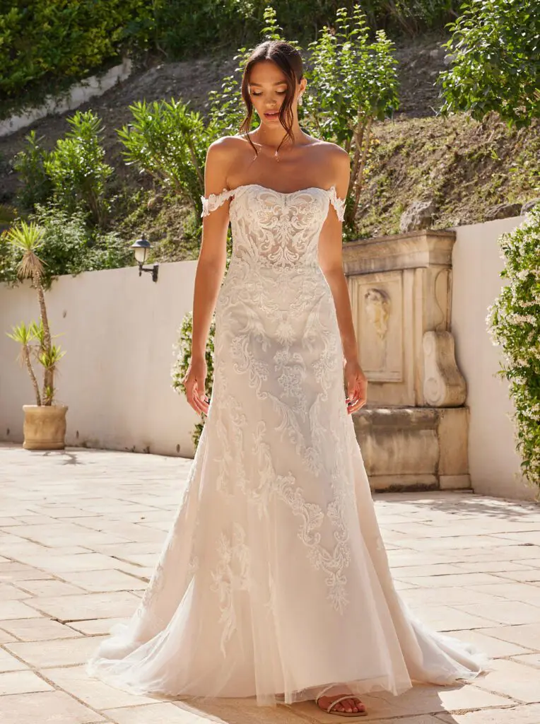 Atemberaubendes Brautkleid in gerader Silhouette, das Eleganz und Raffinesse ausstrahlt. Das figurbetonte Oberteil mit floraler Spitze, geknotetem Rücken, geradem Ausschnitt und zarten Off-Shoulder-Spitzenärmeln sorgt für einen stilvollen Look. Die fließende Spitze über dem Rock mit Schleppe verleiht dem Design Einzigartigkeit und Anmut.