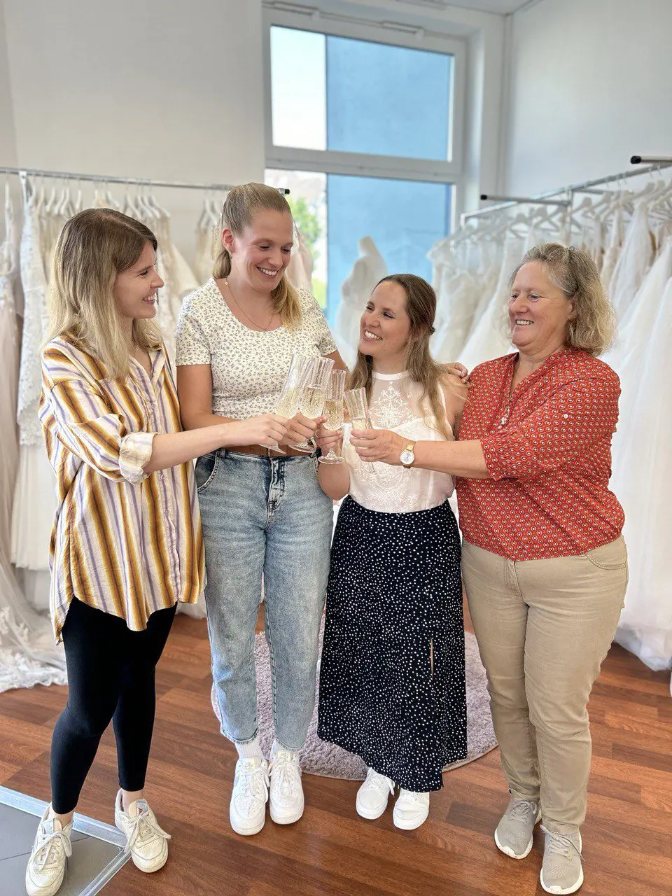 Braut und Begleitung stoßen im Brautgeschäft nahe Wuppertal auf die Kleidanprobe an. Traumhafte Kleider mit Spitze und passende Accessories für die Hochzeit oder das Standesamt.