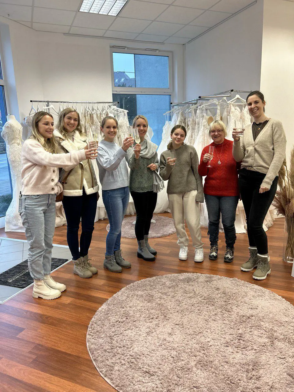 Glückliche Braut beim Anstoßen im Brautgeschäft in der Nähe von Essen. Die Auswahl reicht von schlichten bis hin zu Spitzen-Brautkleidern – perfekte Beratung für die Traumhochzeit.