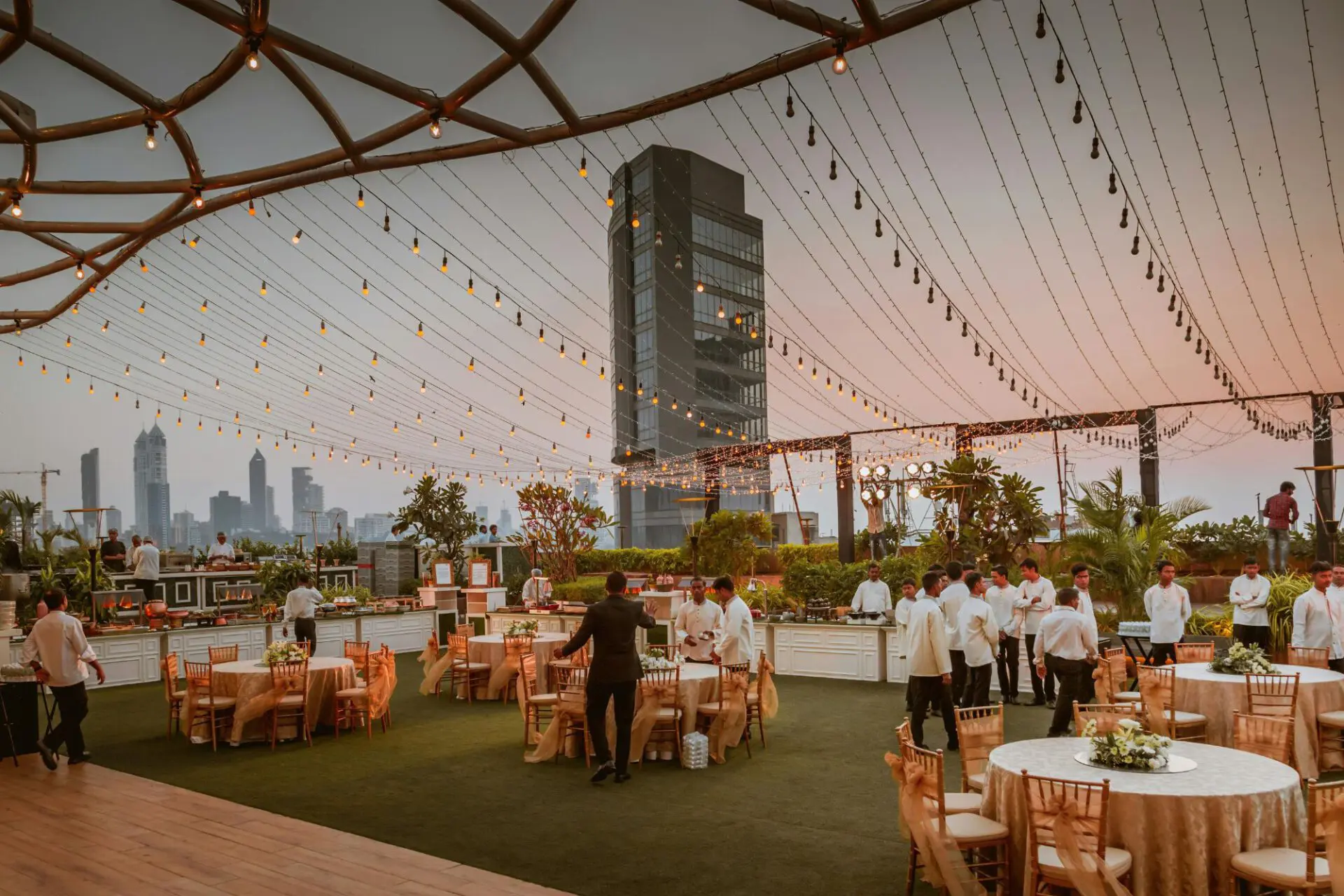 Braut in einem minimalistischen, figurbetonten Brautkleid steht stilvoll auf einer Rooftop-Terrasse mit Stadtblick.